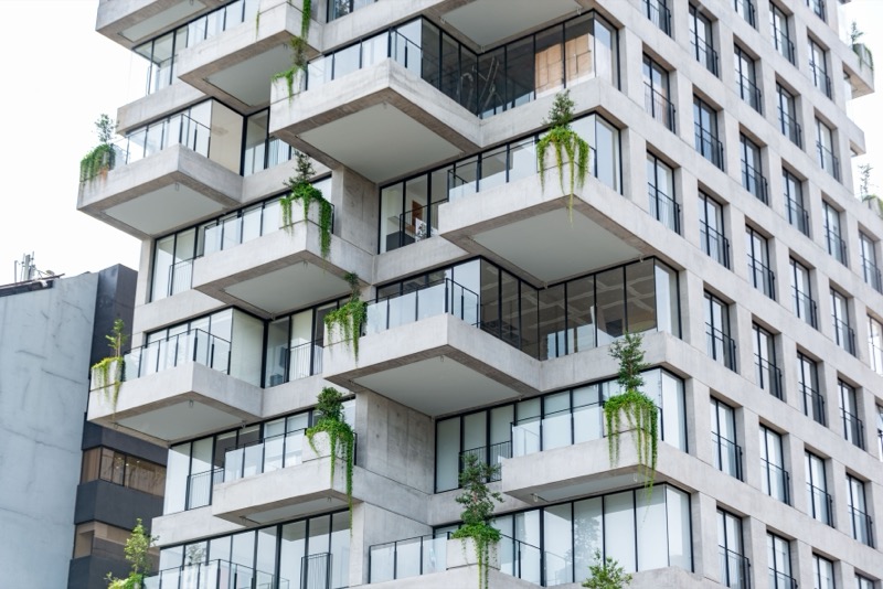 Contemporary residential building featuring geometric design and lush balconies with green plants.