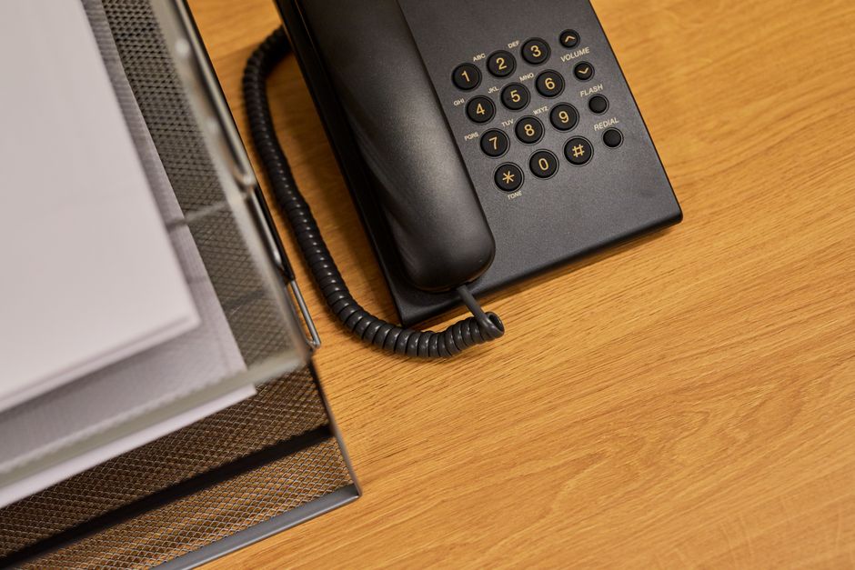 A tidy office desk featuring a classic black telephone and organized documents.